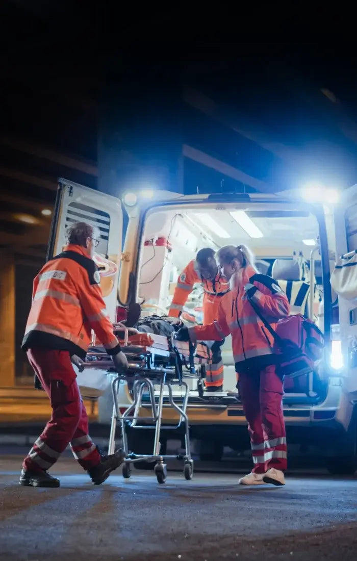 Emergency medical personnel transporting a patient on a stretcher at night.
